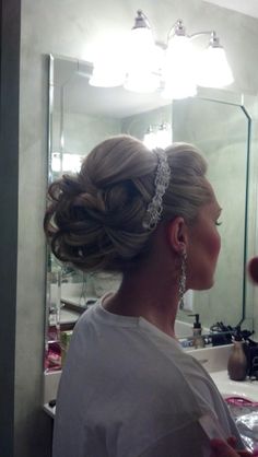 a woman is getting her hair done in front of a mirror with lights on it