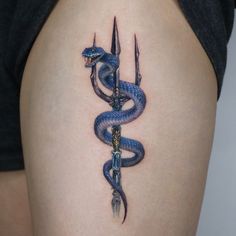 a snake and dagger tattoo on the back of a woman's thigh with scissors