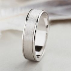 a white gold wedding band is shown on top of a piece of paper with a napkin in the background