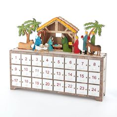 a wooden calendar with nativity scene displayed on it's side and palm trees in the background