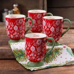 four red coffee mugs sitting on top of a wooden table