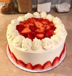 a cake with white frosting and strawberries on top sitting on a countertop