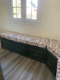 an empty room with a bench and drawers in it, next to a large window