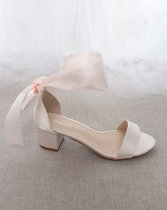 a pair of white shoes with a bow on the heel