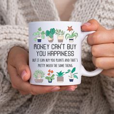 a woman holding a coffee mug that says money can't buy you happiness but it can buy you plants and that's pretty much the same thing