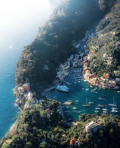 an aerial view of boats in the water near a mountain side town and harbor area