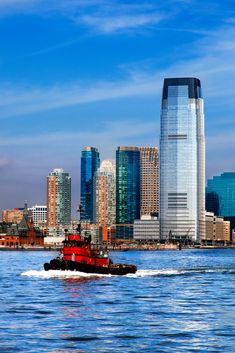 a tug boat in the water near a large city with tall buildings on either side