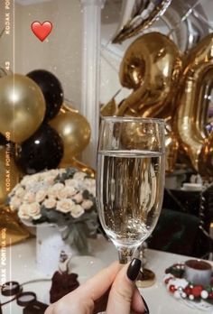 a person holding a wine glass in front of some balloons and other party decorations on a table