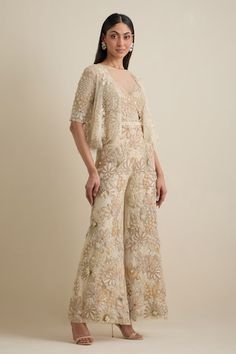 Ivory jumpsuit with all-over cutdana, moti, dabka, sequins, stones resham and crystal embroidery in floral pattern. Comes with shrug style embroidered cropped jacket. - Aza Fashions Fitted Embroidered Jumpsuit For Festive Occasions, Embroidered Fitted Jumpsuits And Rompers For Festive Occasions, Festive Embroidered Fitted Jumpsuits And Rompers, Elegant Embellished Festive Jumpsuits And Rompers, Elegant Embellished Jumpsuits And Rompers For Festive Occasions, Elegant Embellished Jumpsuits And Rompers For Festive Season, White Hand Embellished Evening Sets, Embellished Floor-length Jumpsuits And Rompers For Wedding, Embellished Floor-length Jumpsuit For Wedding