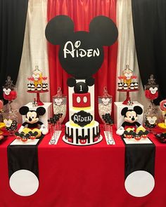 a mickey mouse themed birthday party with red and black tablecloths, cake, cupcakes and decorations