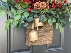 a christmas wreath hanging on the front door with bells and evergreens, berries, and holly