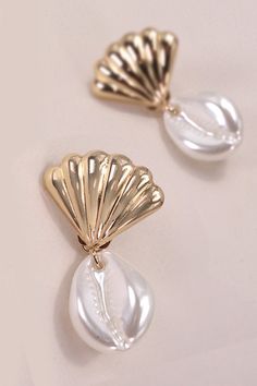 Crafted with care, these earrings feature delicate seashells and authentic puka shells dangling gracefully from each ear. Inspired by the serene allure of the ocean, they infuse your ensemble with a touch of seaside elegance. Perfect for adding a hint of beachy flair to any outfit, whether you're vacationing by the shore or simply longing for coastal vibes. Product Details:Width: 1"Length: 1.5"Earring back: PostMetal finish: gold, rhodium PlatedProduct: Lead & Nickel CompliantAnti-tarnish: Double E-coating Mother Of Pearl Shell With Pearl Drop, Elegant Drop Earrings For Vacation, Elegant Pearl White Shell For Beach, Ocean-inspired Drop Shell Earrings, Dangle Shell Earrings With Pearl Drop, Elegant Pearl Charm Shell For Beach, Dangle Pearl Drop Shell Earrings, Pearl Drop Shell Earrings, Elegant Shell Dangle Earrings