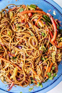 a blue bowl filled with noodles and vegetables