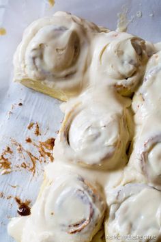 cinnamon rolls with icing sitting on top of a piece of parchment paper