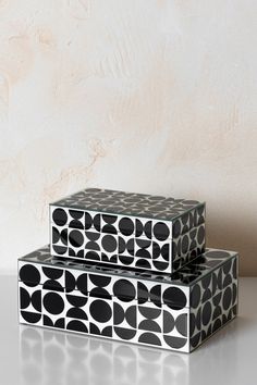 two black and white boxes sitting next to each other on top of a table with a wall in the background