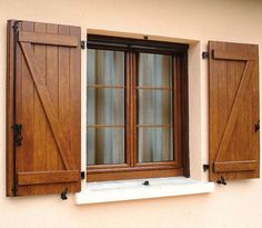 two windows with wooden shutters on the side of a building