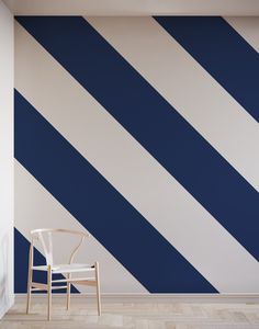 a chair sitting in front of a wall painted with blue and white striped paint on it