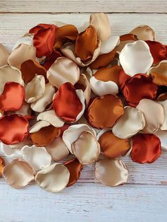 several different colors of fabric flowers on a white wooden surface