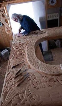 a man working on an intricately carved bench