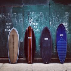 five surfboards are lined up against a wall