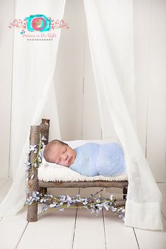 a baby is sleeping on a bed made out of wood and white fabric with flowers around it