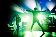 a man standing on top of a stage with his arms outstretched in front of him