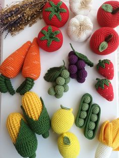 crocheted fruits and vegetables are displayed on a cutting board, including tomatoes, carrots, squash, cornucopies