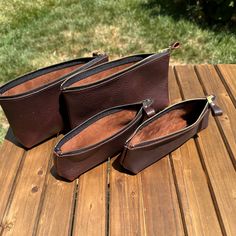 three brown leather purses sitting on top of a wooden table next to each other