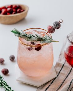 a drink with cranberry and rosemary garnish on the rim