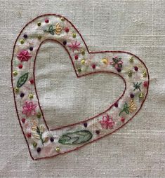 an embroidered heart with flowers and leaves is shown on a piece of linen that has been stitched together