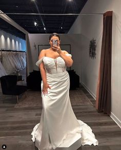 a woman taking a selfie in front of a mirror wearing a white wedding dress