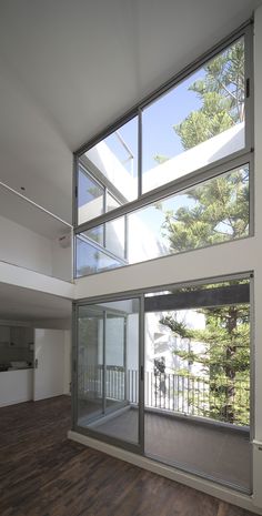 an empty room with wooden floors and large windows on the second floor that overlooks trees