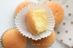 three yellow cupcakes sitting on top of each other in paper liner cups with one bite taken out