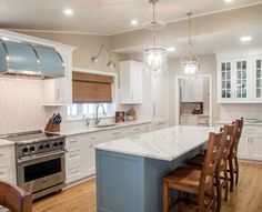 a large kitchen with white cabinets and marble counter tops, an island in the middle