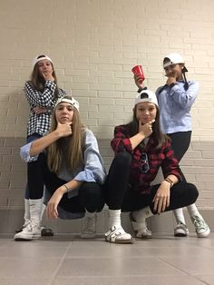 four girls are posing in front of a brick wall and one girl is holding a red cup