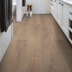 a kitchen with white cabinets and wood flooring on the walls, along with a stool