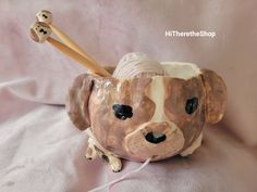 a ceramic dog figurine with a baseball bat in it's mouth on a pink blanket