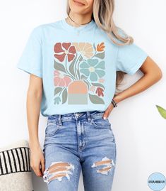 🌼Discover our Retro Boho Floral Comfort Colors shirt!🌼 This trendy Colorful Flower t-shirt features an eye-catching boho graphic design that is sure to enhance your outfit! Made of 100% ring-spun ethically grown cotton, this shirt is super soft and comfortable. It has a relaxed fit which is made of a medium fabric that is preshrunk. Looks super cute with shorts, jeans or as an oversized beach cover up. Great gift idea for a Boho Lover! Comes in 12 pretty colors! ♦️Please let me know if you do not see the color shirt you would like.♦️ 💠PRINT: This is a handmade, Direct-to-Garment printed item. The designs are professionally printed directly on to the shirt. All over printing is used. The ink is printed directly into the fabric. ✦Images may sometimes appear larger in the photo than in per Retro Floral Print T-shirt With Short Sleeves, Blue Floral Print Graphic Tee, Blue Graphic Tee With Floral Print, Blue Floral Print Graphic Tee Shirt, Multicolor Crew Neck T-shirt With Plant Print, Trendy Crew Neck Shirt With Plant Print, Casual Light Blue Printed T-shirt, Trendy Blue Floral Print T-shirt, Blue Floral Print Crew Neck Shirt