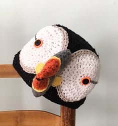 a crocheted bird hat sitting on top of a wooden chair