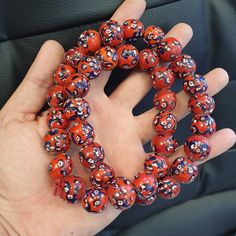 a hand holding a red and blue beaded bracelet