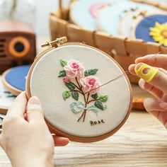 a woman is stitching flowers on an embroidery hoop