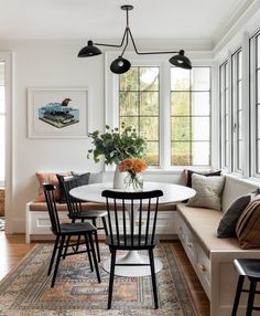 a dining room table with four chairs and a bench in front of the window,