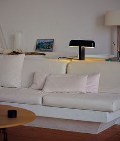 a living room with white couches and lamps on the side tables in front of them