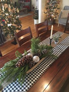 a dining room table decorated for christmas with pine cones and greenery in a box