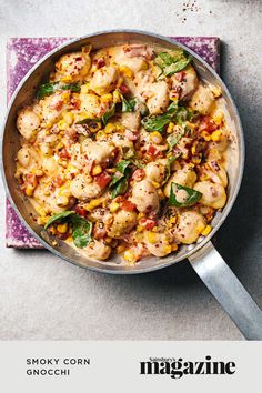 a pan filled with chicken, corn and spinach on top of a purple napkin