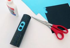 a pair of scissors and glue sitting on top of a piece of paper next to some cut outs