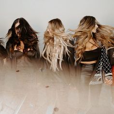 three beautiful young women standing next to each other in front of a white wall with long hair