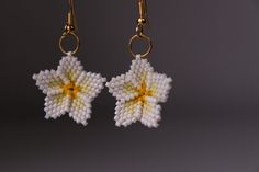 a pair of white and yellow beaded flowers on gold earwires, hanging from hooks