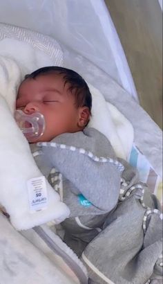 a baby is sleeping with a pacifier in it's mouth and wrapped in a blanket