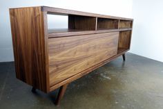 a large wooden cabinet sitting on top of a cement floor next to a white wall